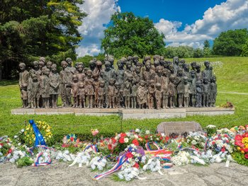 das Denkmal für die 83 ermordeten Kinder mit den niedergelegten Blumen