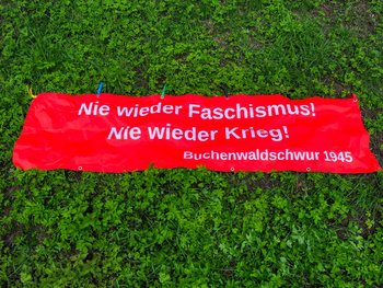 Rotes Banner mit der Aufschrift:„Nie wieder Faschismus! Nie wieder Krieg! Schwur von Buchenwald“