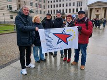Mitglieder SFEL-R vor der Botschaft der USA mit der Fahne der Europäischen Linken-