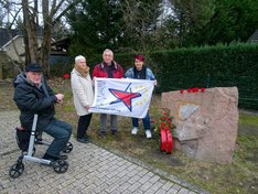 Genossen mit der Fahne der Europäischen Linken am Gedenkstein