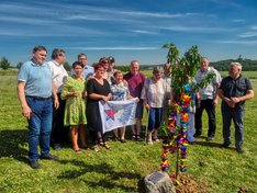 Teilnehmer des Koordinierungsrates an dem gepflanzten Kirschbaum mit der Erinnerungsplakette
