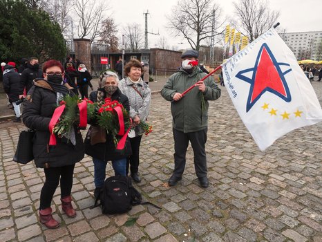 Mitglieder des SFEL-R mit den Blumengestecken und einer Fahne der Europäischen Linken